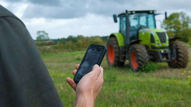 farmer holding phone with tractor in background