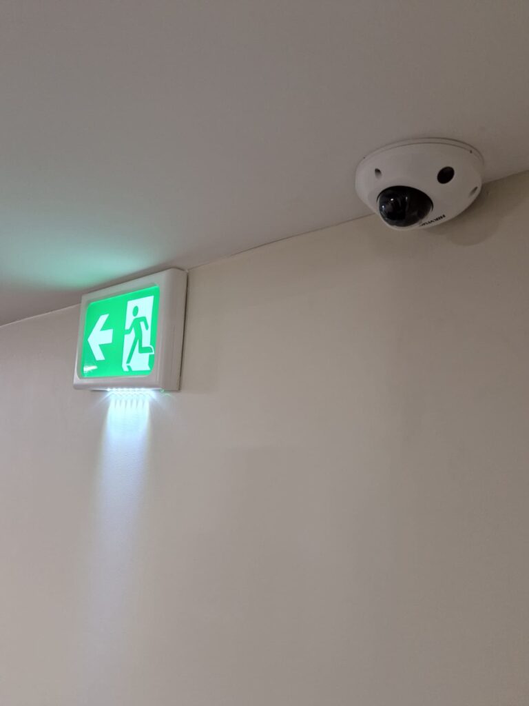 cctv camera in corner beside emergency exit sign